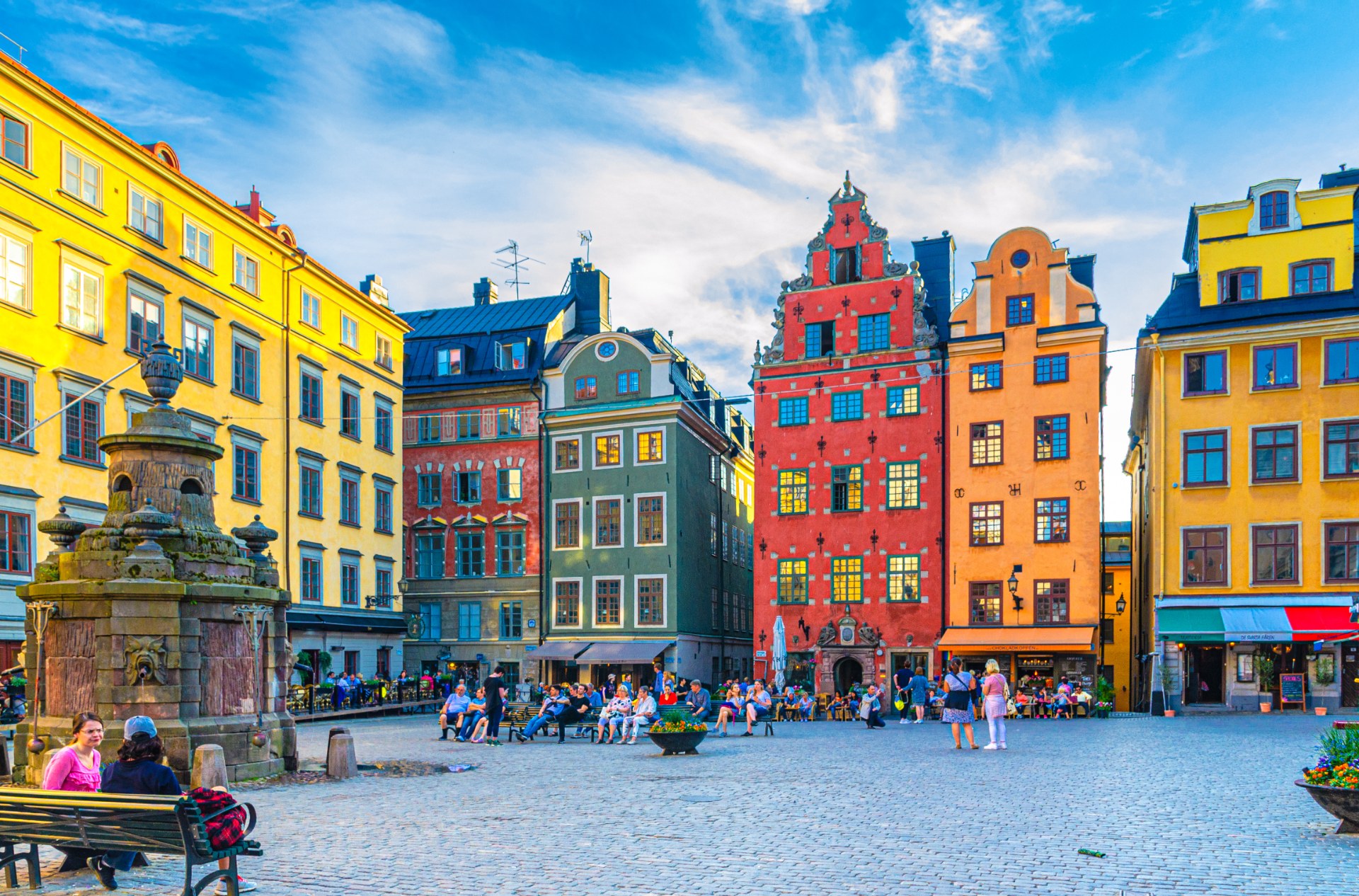 Stokholm’daki Stortorget Meydanında renkli evlerin arasında turistler ve yoldan geçenler